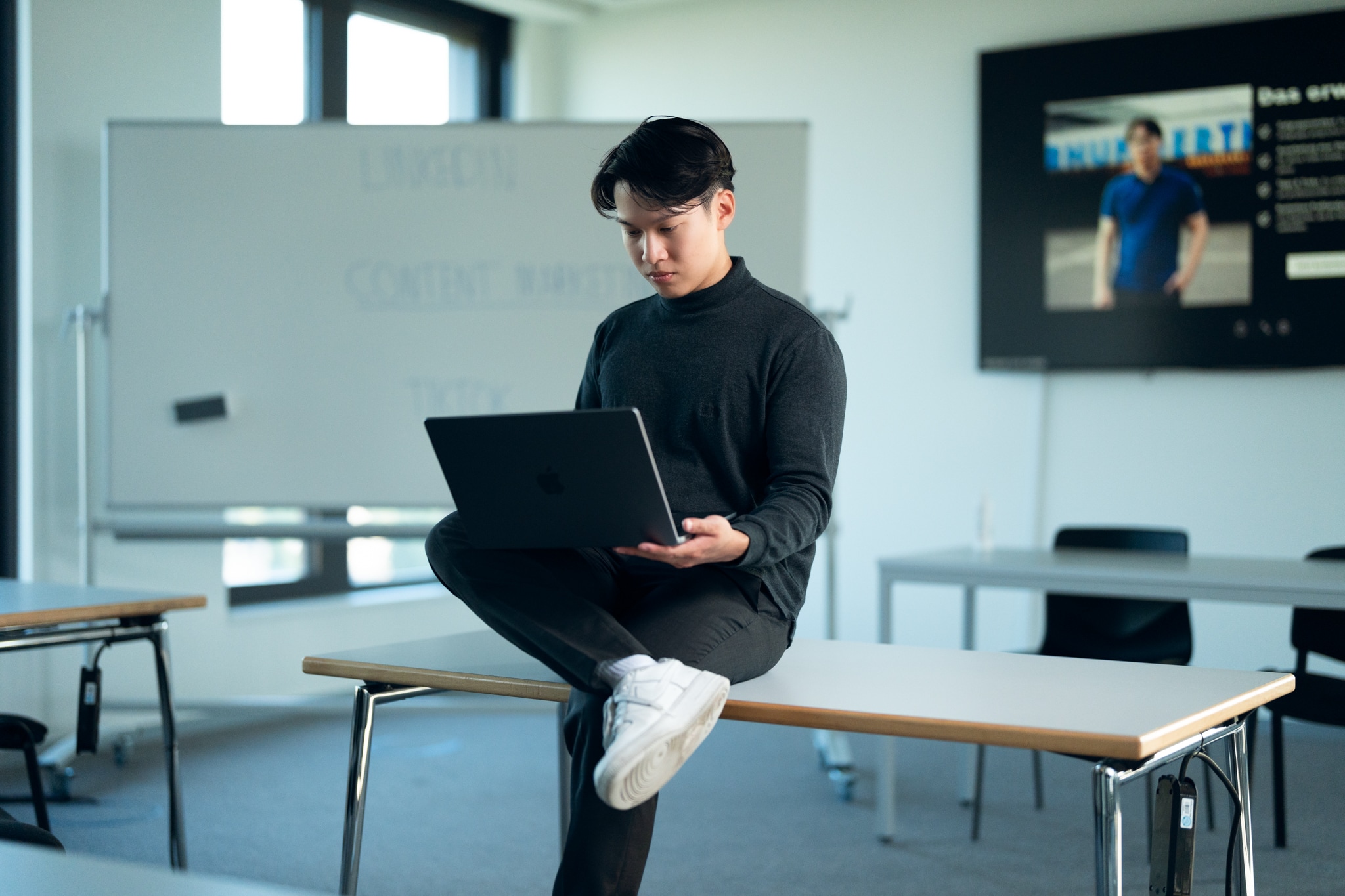 Jackson Ly sitting on a table and working on a laptop